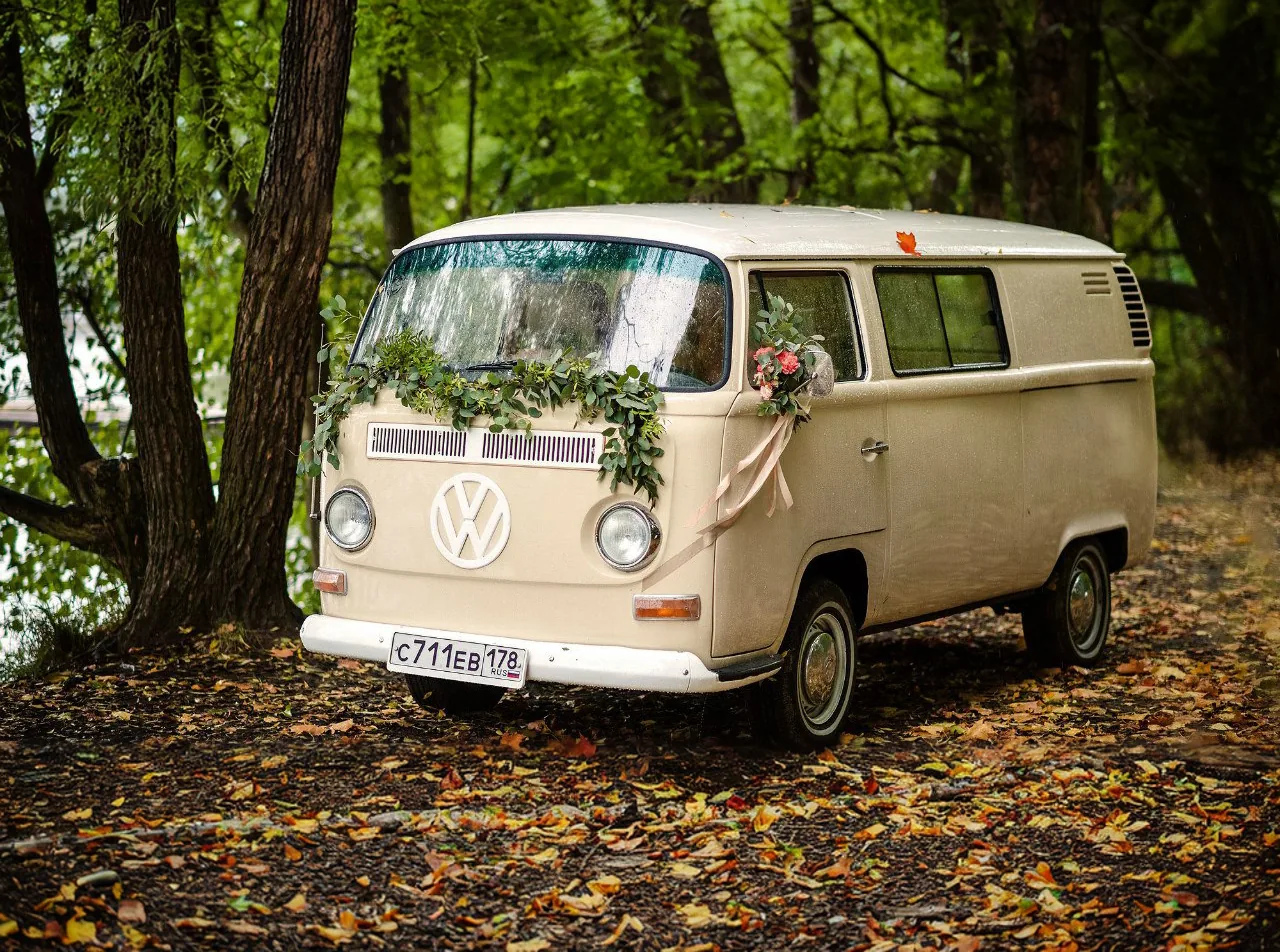 Кремовый Volkswagen T2 с гирляндой из зелени и букетом на капоте в осеннем лесу